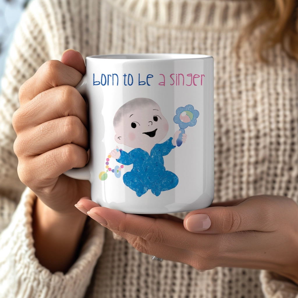 Playful nursery coffee mug featuring a cartoon baby boy holding a rattle, with the text "Born to be a singer”, close-up, size: 11oz, free shipping, USA, kidlic