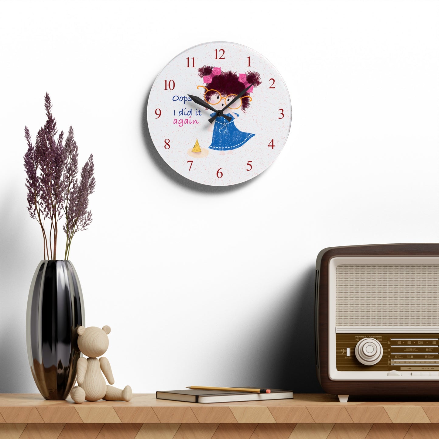 Charming humorous acrylic wall clock hanging on a white wall featuring a cartoon girl with curly hair, oversized glasses, and a blue dress, standing next to a fallen ice cream cone, with the text 'Oops, I did it again' alongside red numbers on the clock face, size 10.75”x10.75” (round), kidlic