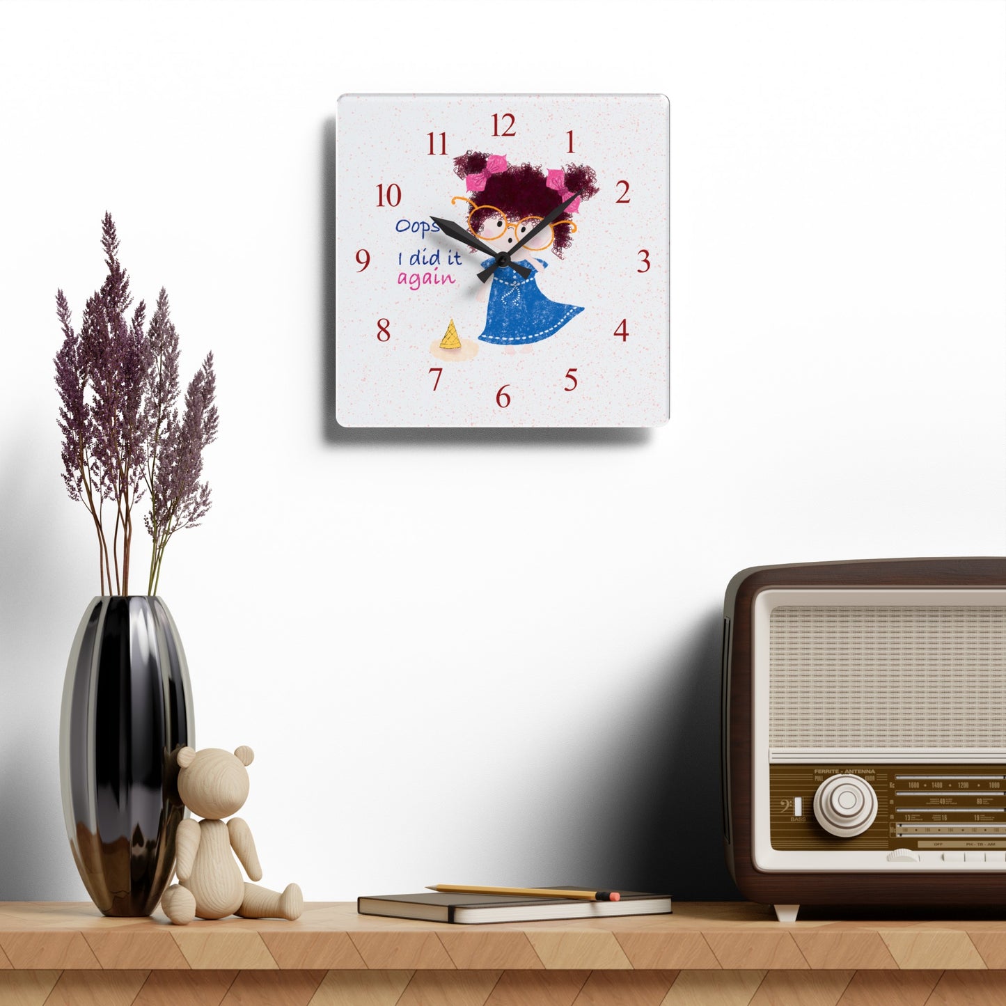 Charming humorous acrylic wall clock hanging on a white wall featuring a cartoon girl with curly hair, oversized glasses, and a blue dress, standing next to a fallen ice cream cone, with the text 'Oops, I did it again' alongside red numbers on the clock face, size 10.75”x10.75” (square), kidlic