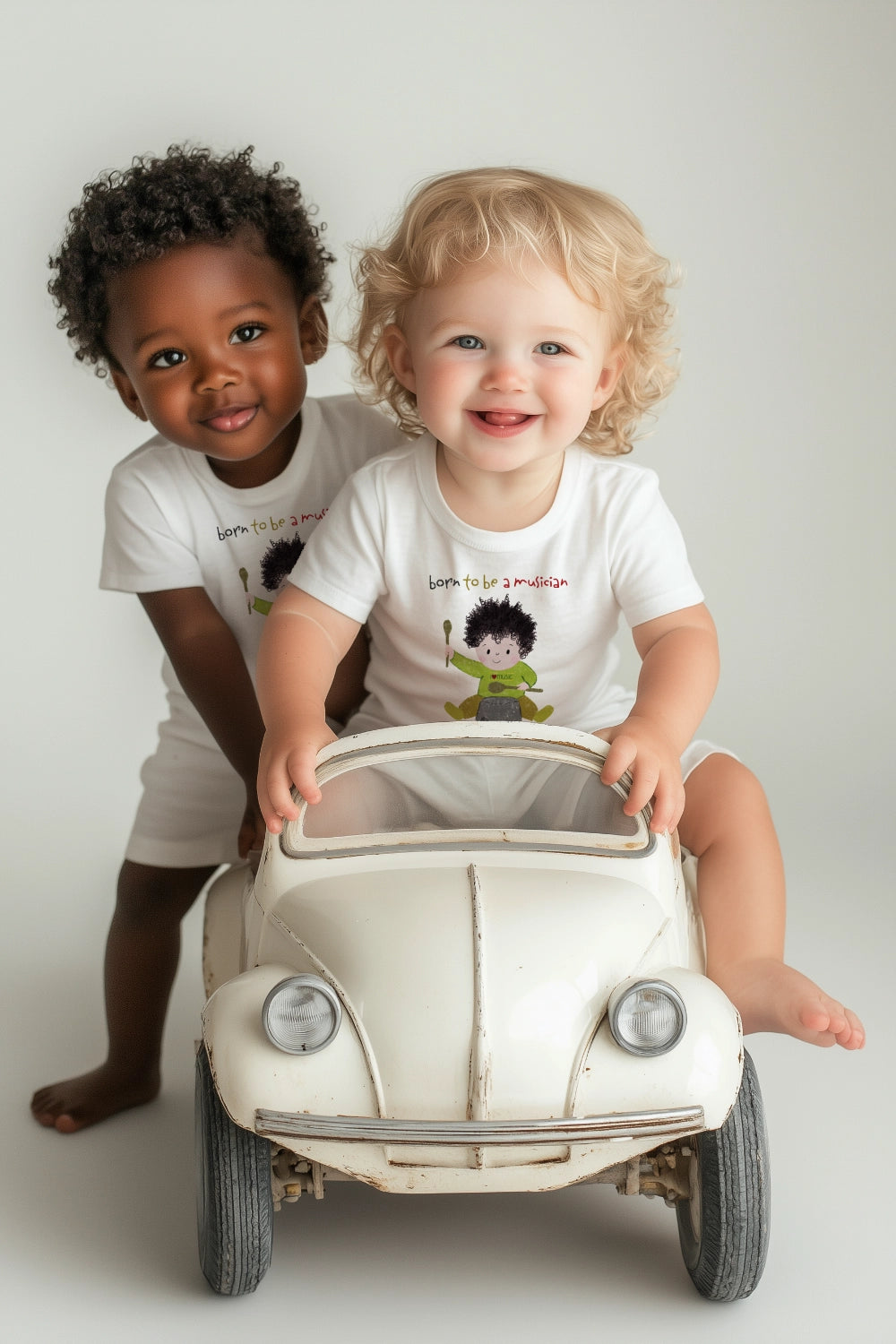 Two preschool boys wearing white tshirts featuring a cartoon baby boy playing a pot with a wooden spoon, with the text 'Born to be a musician’, free shipping, USA, kidlic