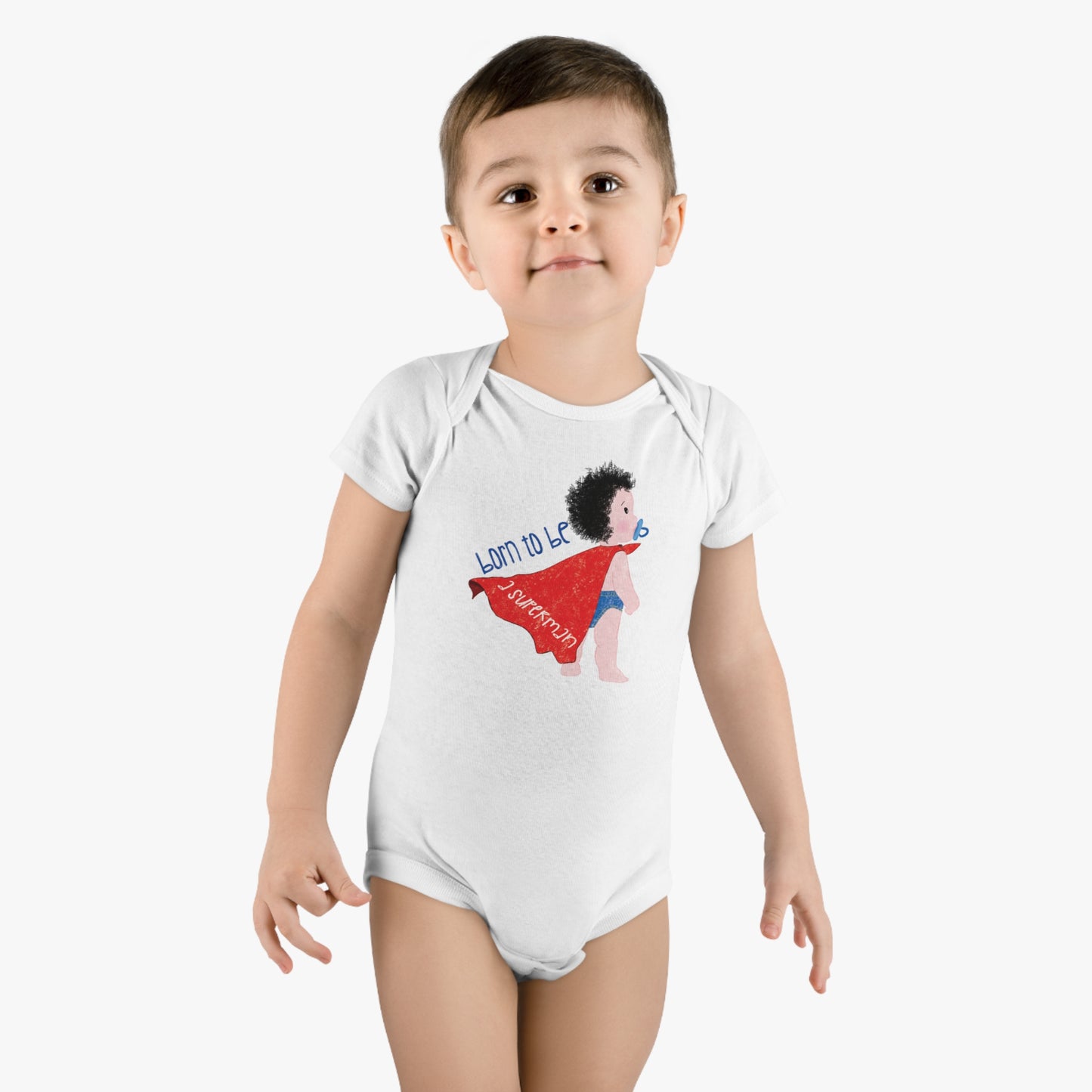 Boy wearing Humorous Organic Baby Onesie featuring a cartoon baby with a pacifier, wearing a red cape, with the text 'Born to be a superman’, free shipping, kidlic