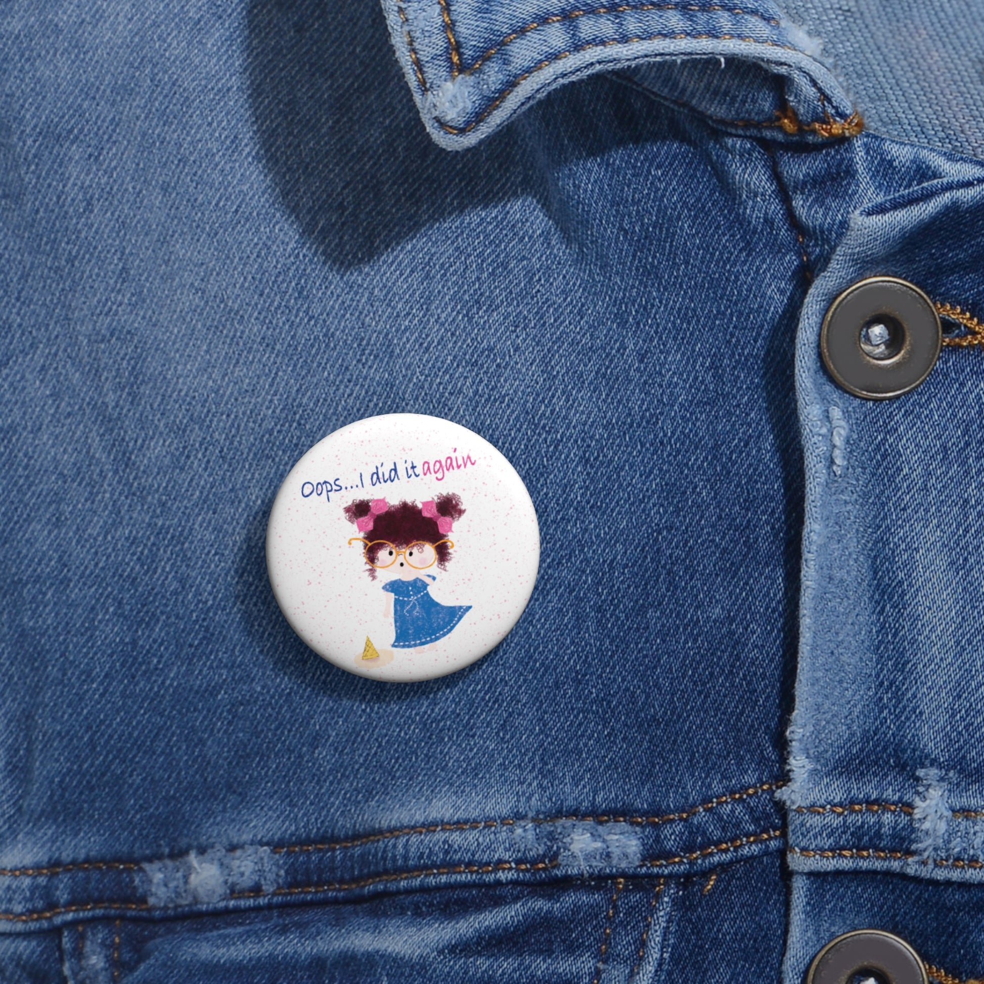 Hilarious nursery round pin button featuring a cartoon girl with curly hair, oversized glasses, and a blue dress, standing next to a fallen ice cream cone, with the text 'Oops... I did it again’, size 1”, close-up, kidlic