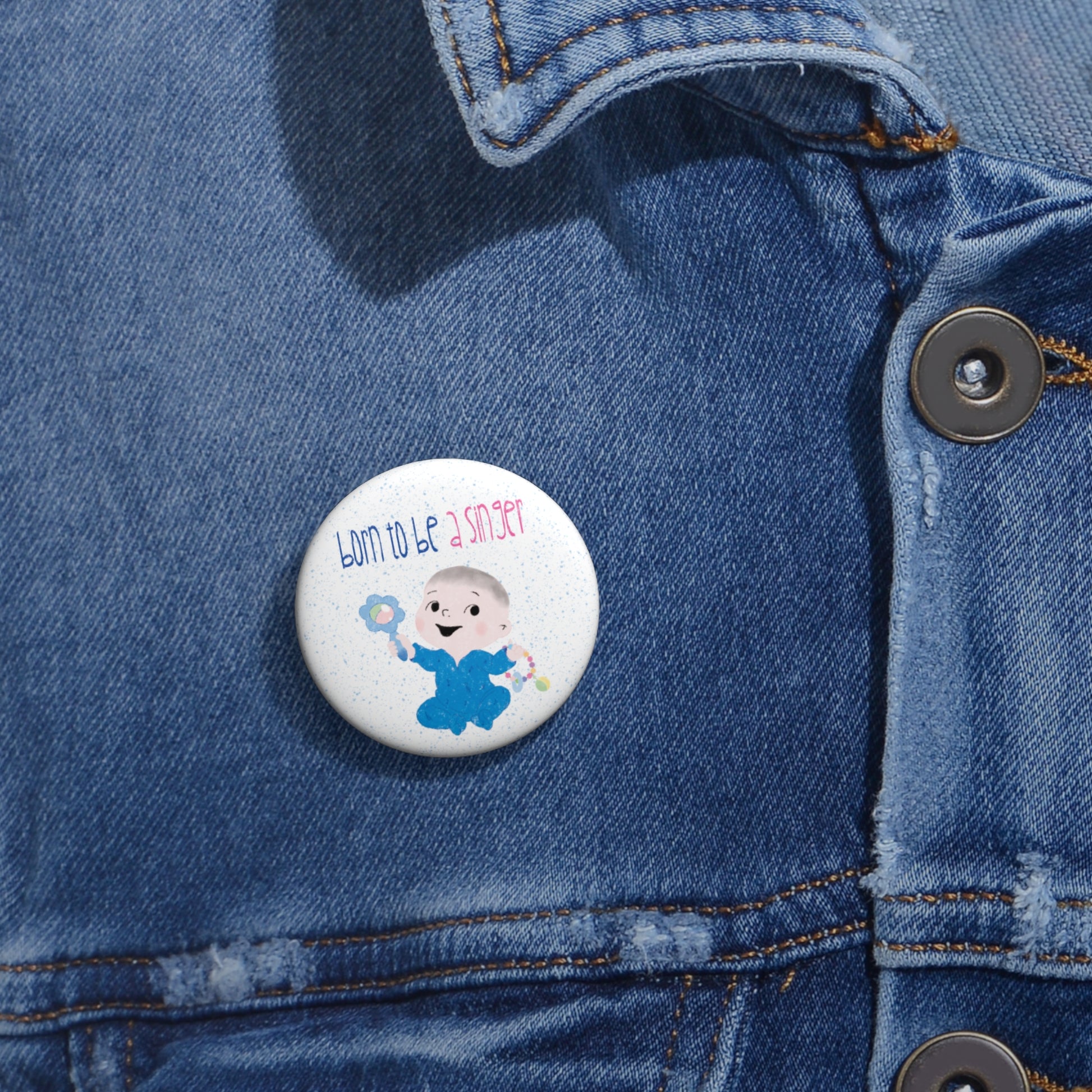 Funny baby nursery singer-themed pin button featuring a cartoon baby boy holding a rattle, with the text "Born to be a singer”, close-up, 1” size, kidlic