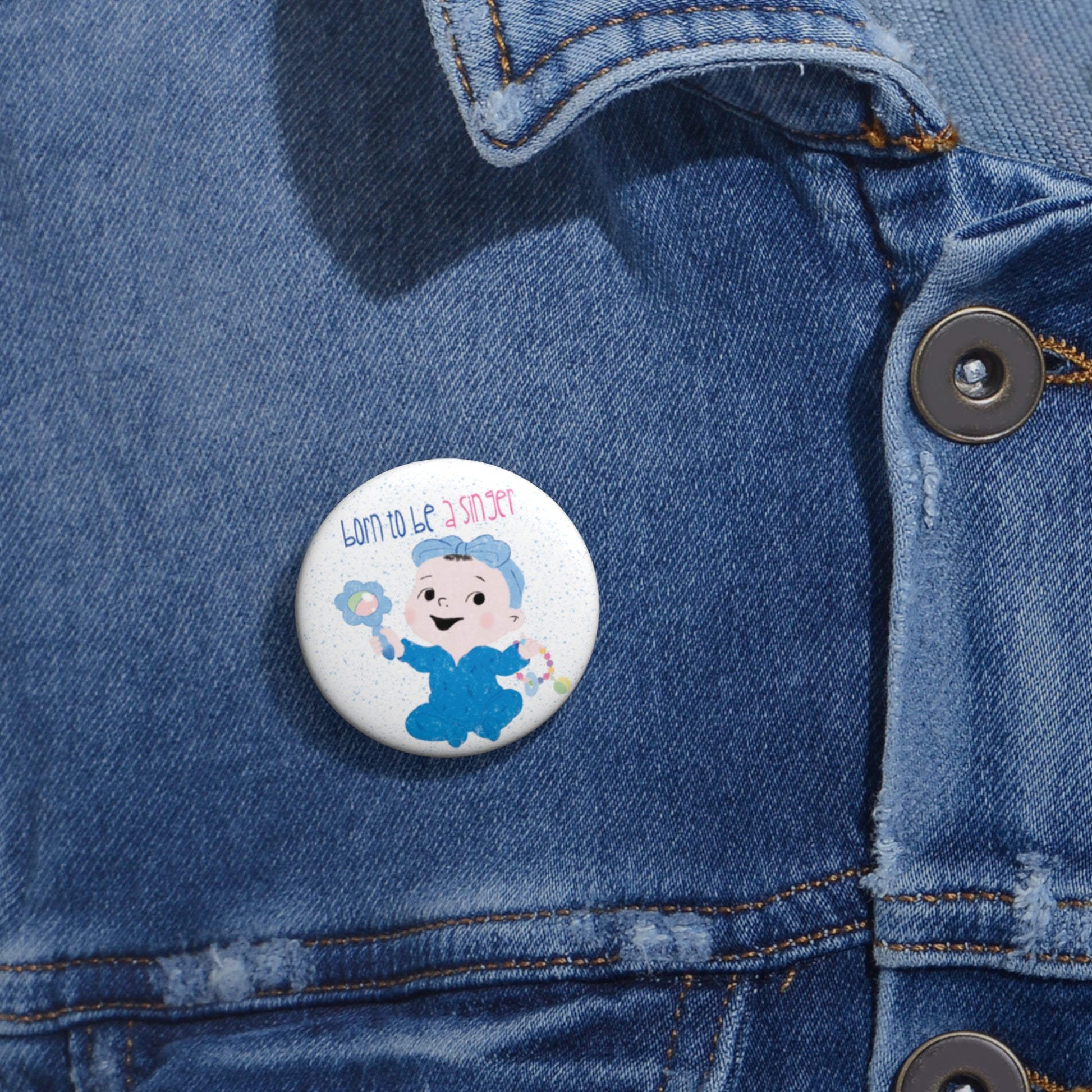 Playful nursery pin button featuring a cartoon baby girl holding a rattle, with a text “Born to be a Singer”, size 1”, close-up, free shipping, kidlic