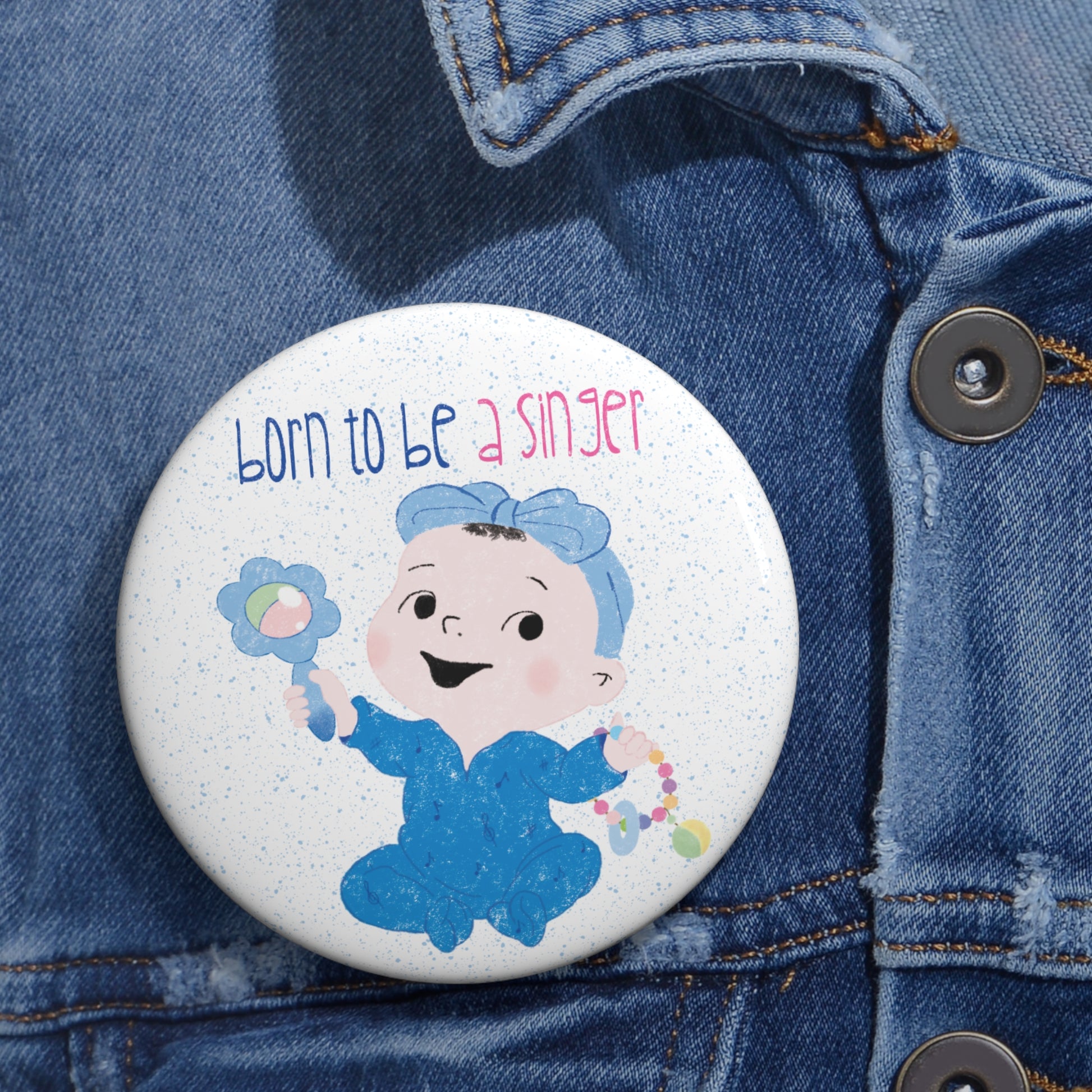 Playful nursery pin button featuring a cartoon baby girl holding a rattle, with a text “Born to be a Singer”, size 3”, close-up, free shipping, kidlic